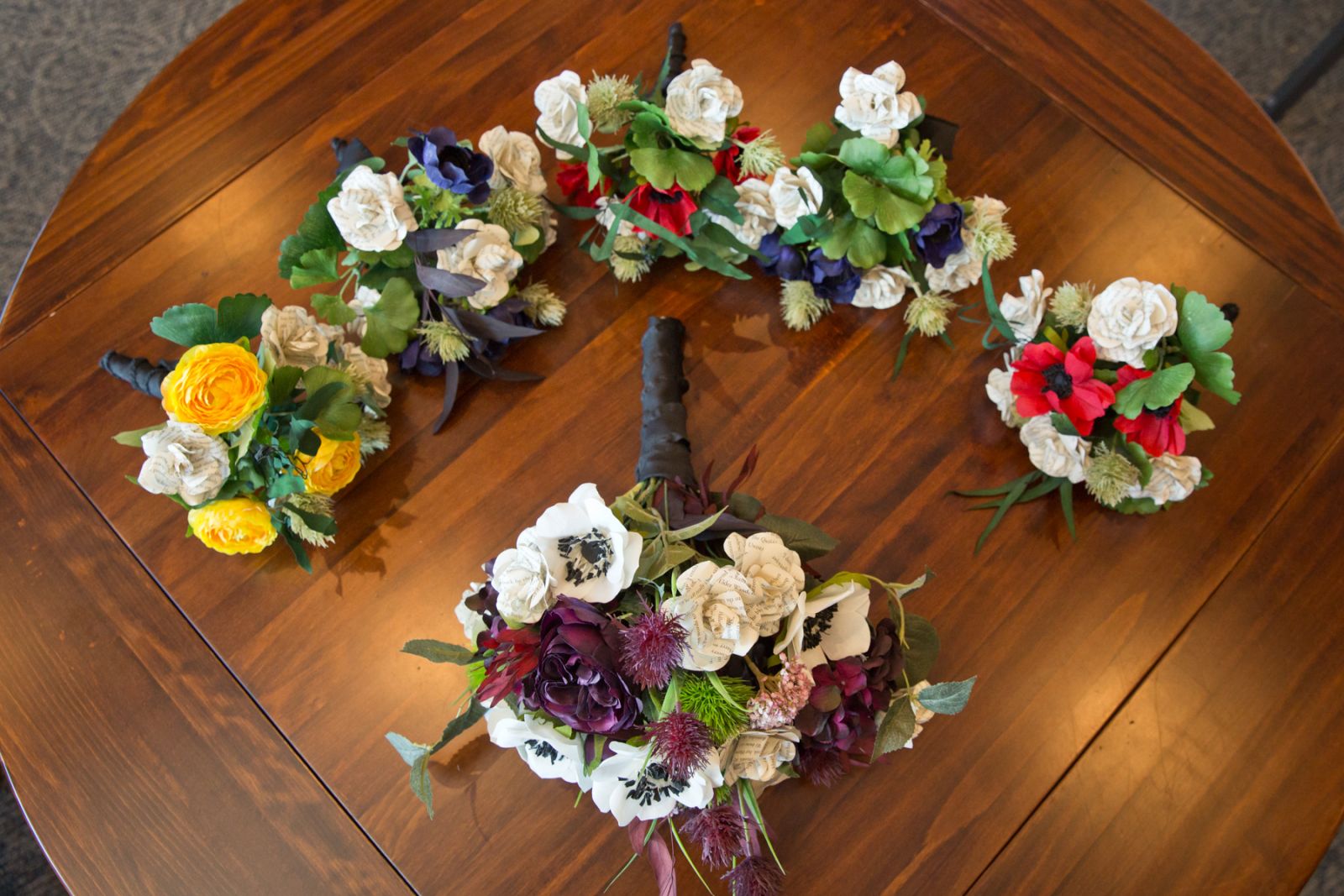 Colorful paper flower wedding bouquets arranged on a wooden table
